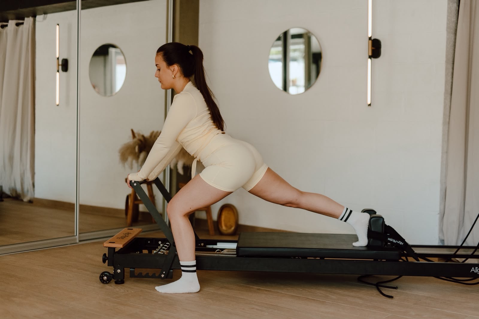 Pratiquante en fente sur le Reformer face au miroir du studio